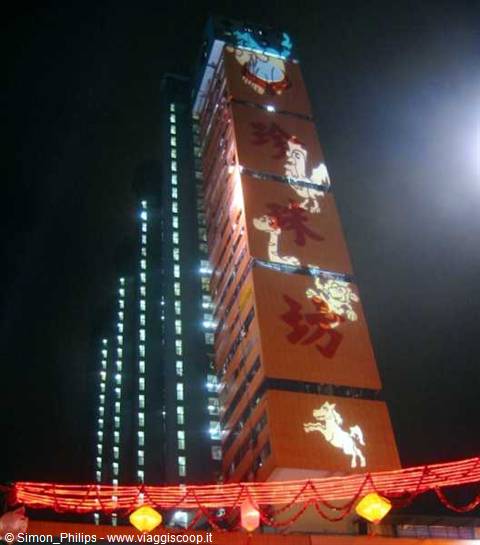 Orange skyscraper with glowing Chinese characters and red lanterns at night