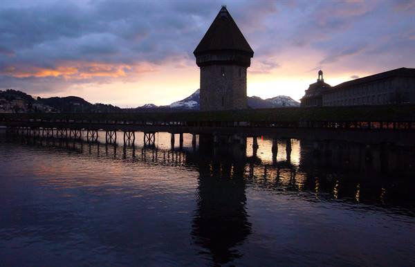 Lucerne: octagonal stone and wood Water Tower reflected in water at dusk