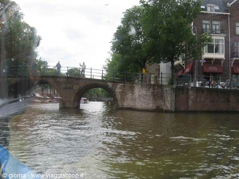 Brick bridge over Amsterdam canal with cyclists and Dutch houses