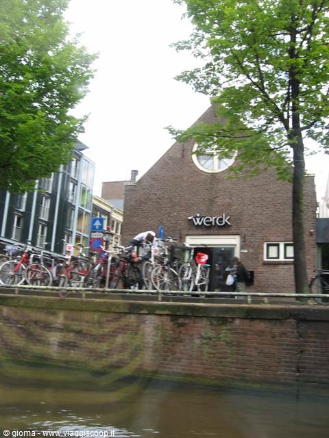 Bicycles parked beside a brick building along the canal