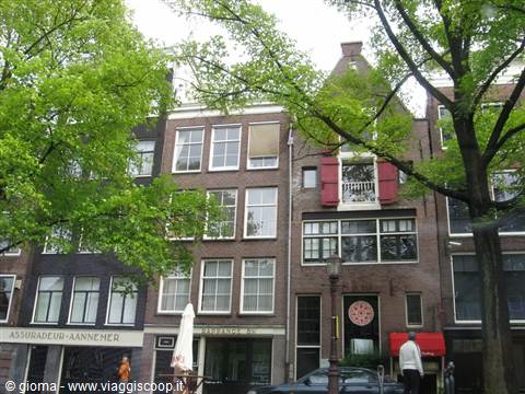 Brick gabled houses in Amsterdam, leafy trees and pedestrians on the street