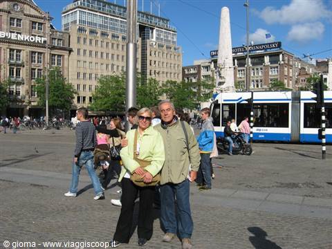 Coppia sorridente in Dam Square ad Amsterdam, tram in arrivo, luce solare
Smiling couple on Amsterdam's Dam Square, blue tram passing, sunny light