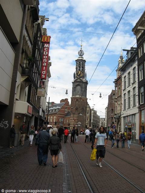 Pedestrians walking along tram tracks toward the Munttoren in Amsterdam