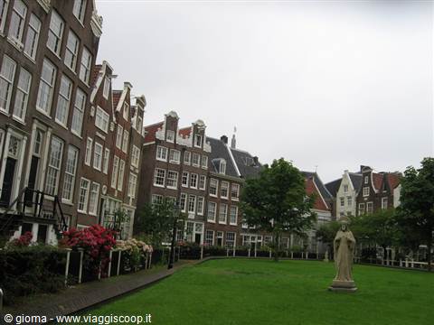 Brick medieval houses and a statue on the lawn of the Begijnhof, Amsterdam