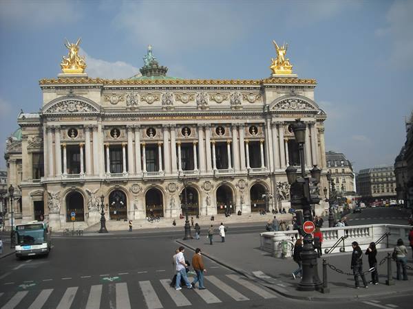 Palais Garnier in Paris, stone facade with golden statues, pedestrians crossing