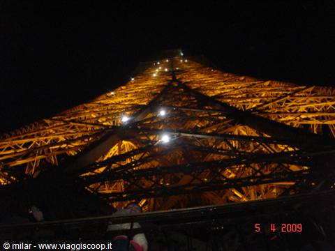 The Eiffel Tower glowing golden at night, shot from below