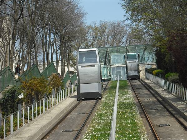 Two Montmartre funicular cars climb between grassy tracks and bare trees