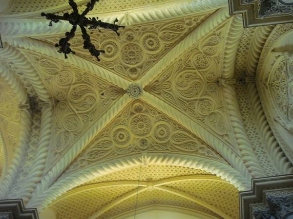 Carved stone vault ceiling with rosettes and decorated ribs under warm light