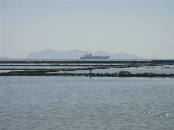 Cargo ship on the horizon between salt pans and hazy islands