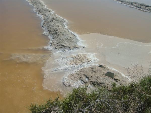 White salt deposits between ochre brine ponds in salt evaporation pans