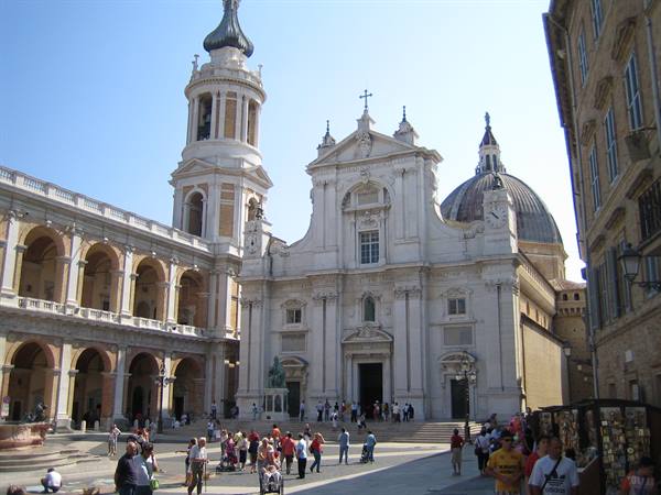 Loreto square: tourists in front of the white basilica with dome and arcade