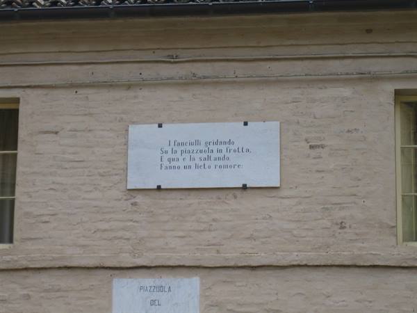 Marble plaque with Guareschi's verses on a pale brick wall