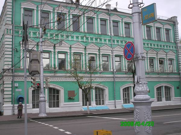 Historic green building with white ornaments, traffic lights and lampposts at an intersection