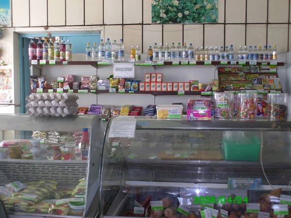 Grocery counter with bottled drinks, eggs and sweets on lit shelves