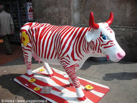 Cow sculpture painted with red stripes, street art installation