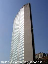 Glass and grey stone skyscraper against blue sky, traffic below