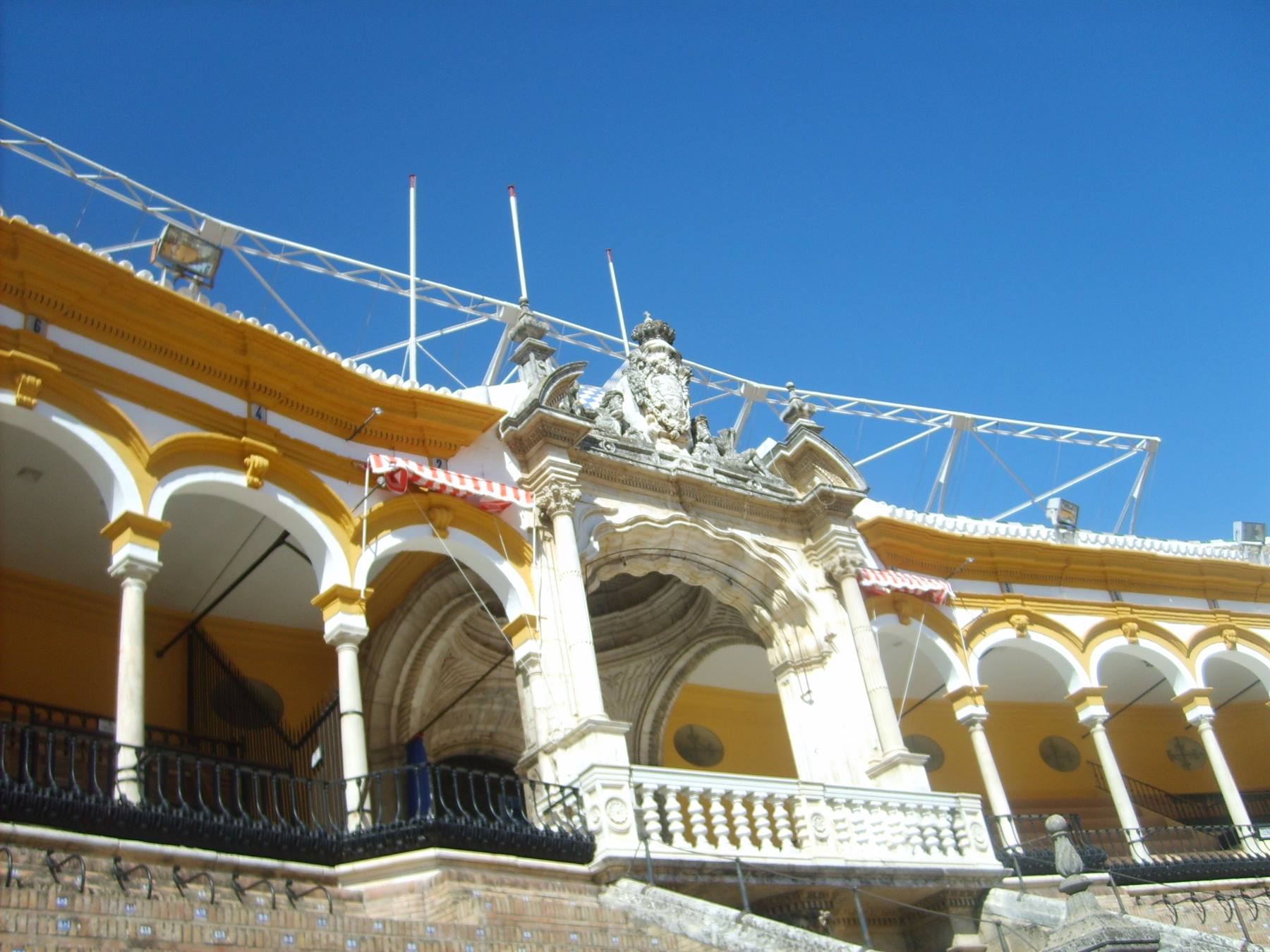 Yellow and white arches of Seville's bullring under a blue sky