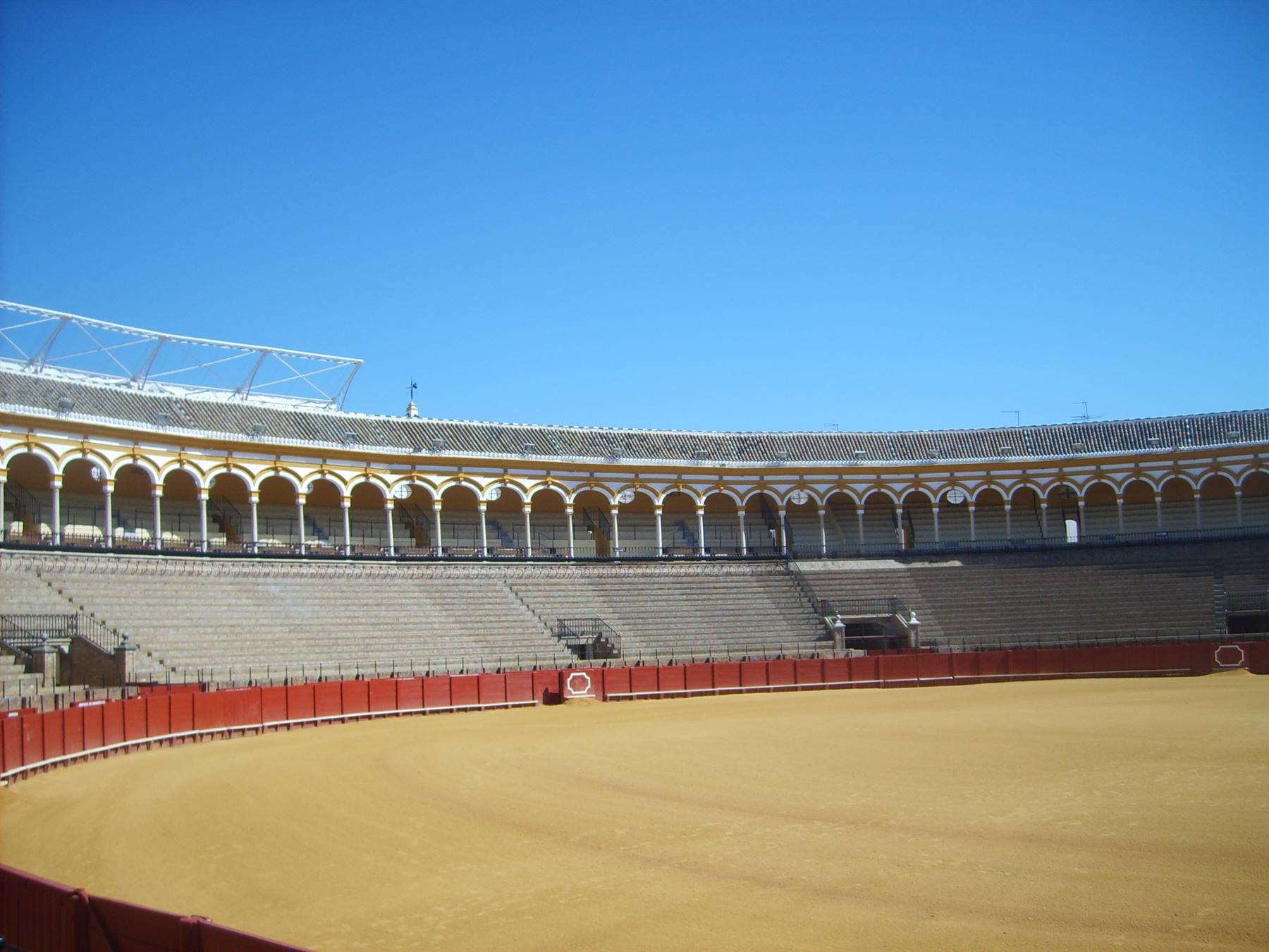Bullring arena in Seville, yellow sand and white arcades