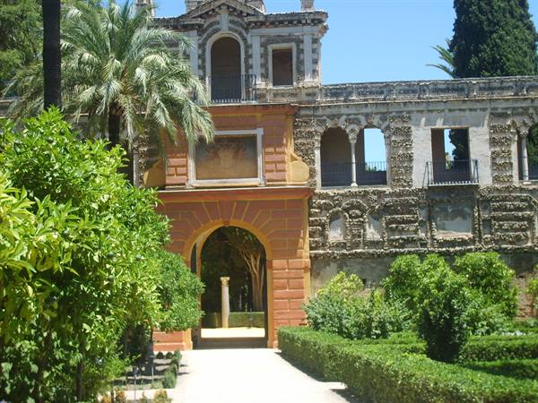 Gardens of the Alcázar of Seville, brick archway and green hedges in sunlight