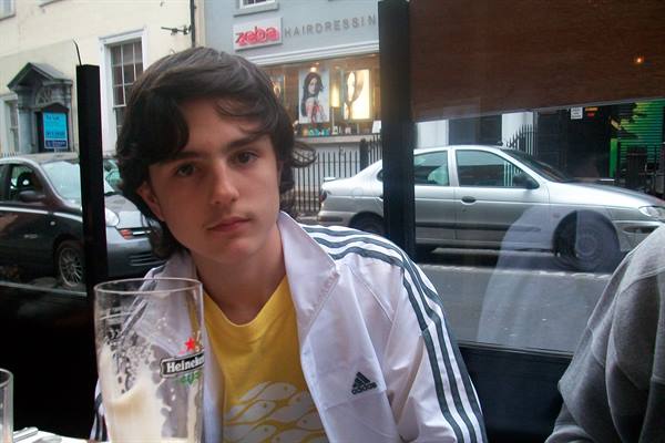 Boy in white Adidas jacket drinking a Heineken at the pub