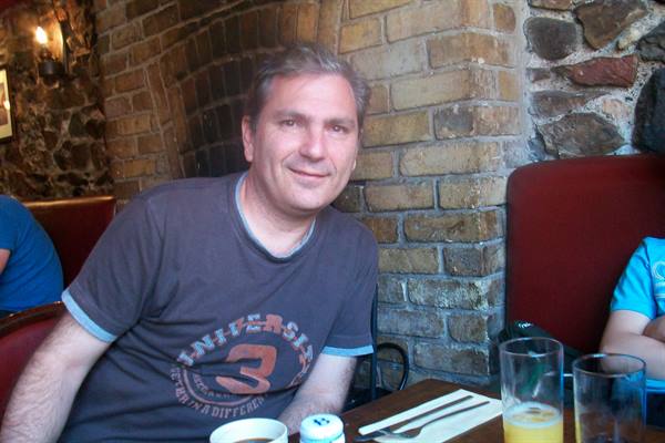 Smiling man at a brick pub table with glasses and cutlery