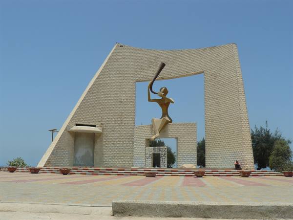 Brick monument with golden statue of a woman blowing a horn
