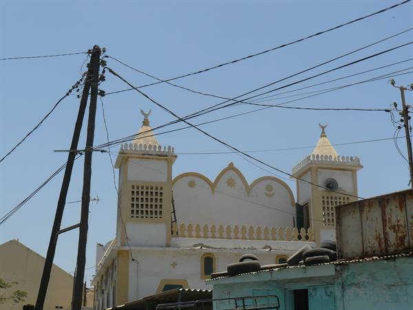 White and yellow mosque with twin minarets among power lines, Saint-Louis