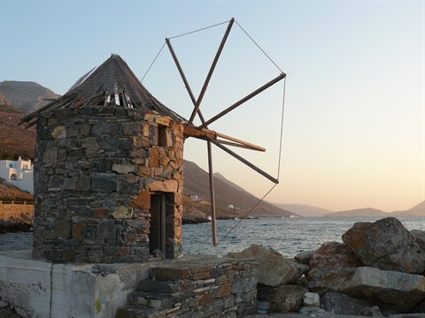 Old stone windmill with wooden sails overlooking the sea
