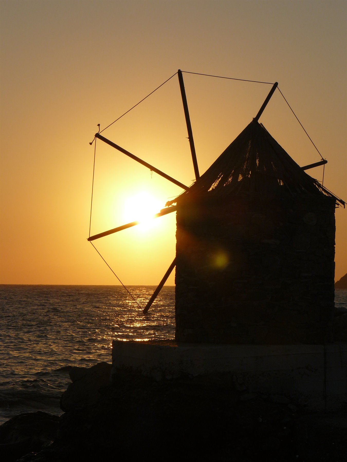 Mulino a vento in pietra in controluce sul mare