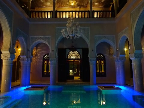 Patio con piscina illuminata di blu e lampadario, riad di Marrakech