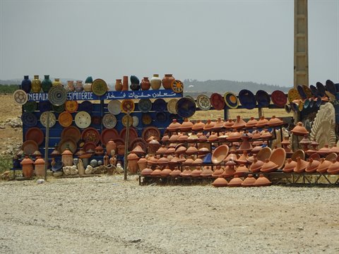 Colorful pottery and clay tagines displayed at a roadside stall near Marrakech