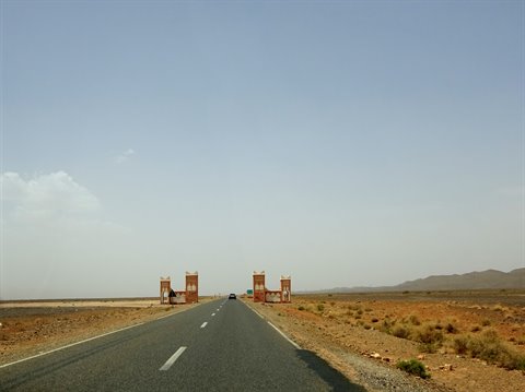 Strada asfaltata tra portali in mattoni nel deserto vicino a Errachidia