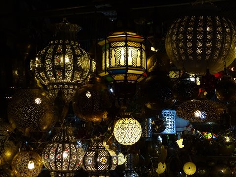 Lit perforated brass lanterns hanging in a Marrakech shop