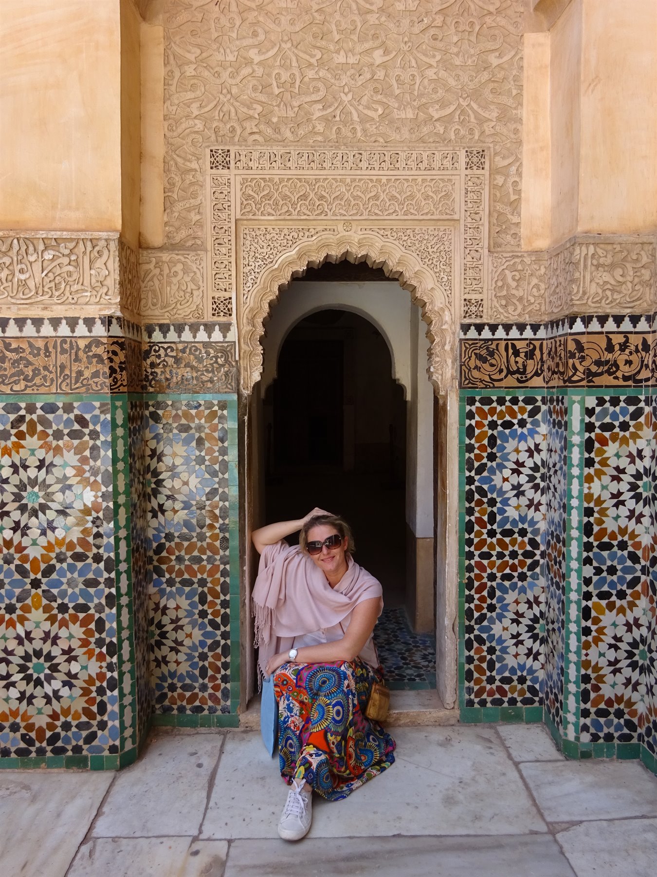 Donna sorridente accanto a porta ad arco con zellige a Fes