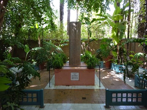 Stone column on pink pedestal in Rabat garden, surrounded by lush green plants