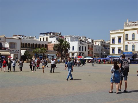 Busy square in Essaouira, white and blue buildings under clear sky