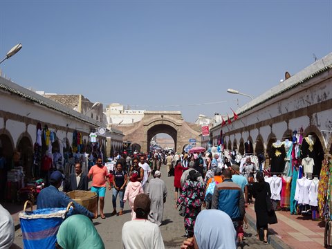 Essaouira market crowds browsing stalls under arcades near the historic gate