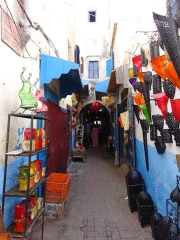 Essaouira alley with colorful lanterns hanging between blue and white walls