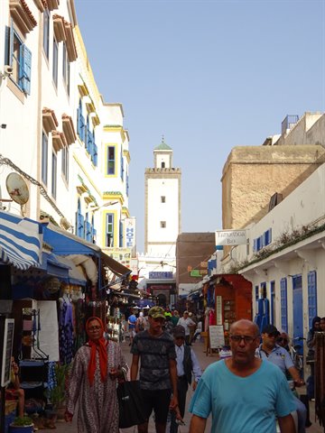 Busy street in Essaouira, white houses with blue shutters and a minaret