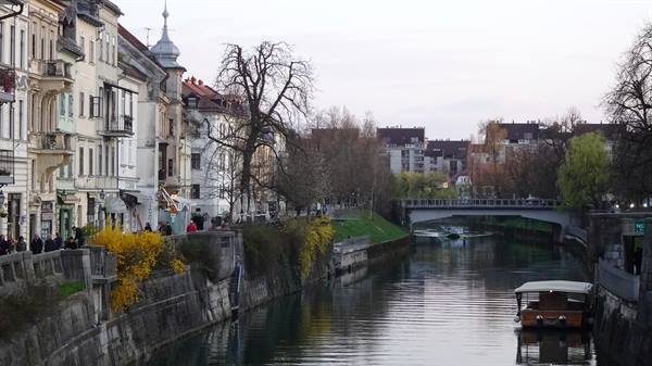 Ljubljanica river in Ljubljana, moored boats, old buildings and footbridge