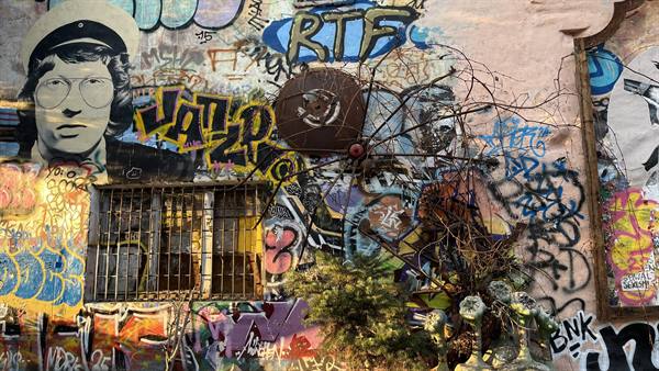 Wall covered with colorful graffiti, stencil portrait, barred window and dry branches