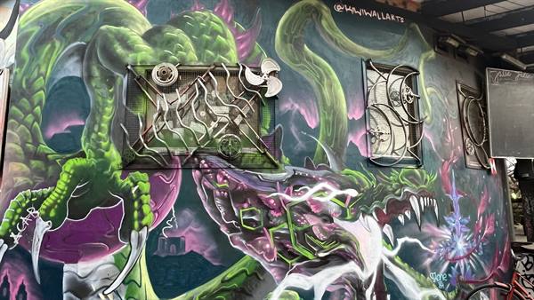Graffiti mural of green and purple dragons on urban wall in daylight