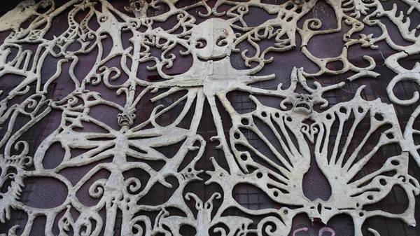 White bone carvings of fantastic figures on a dark wall