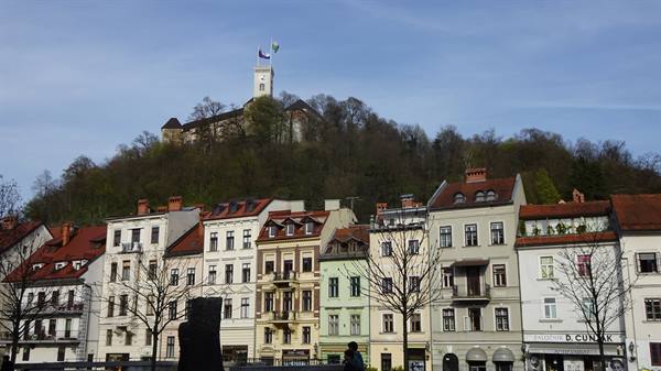 Colorful facades with red roofs beneath Ljubljana Castle on the hill