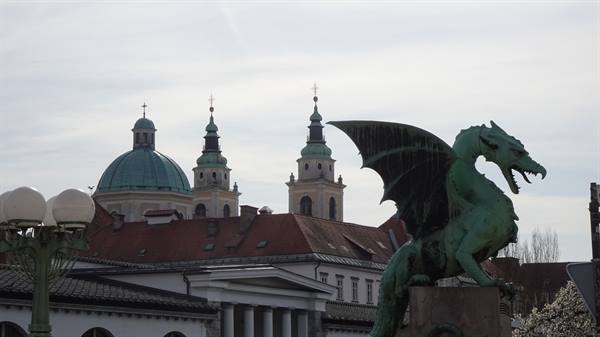 Green copper dragon statue on the bridge, Ljubljana dome and bell towers behind