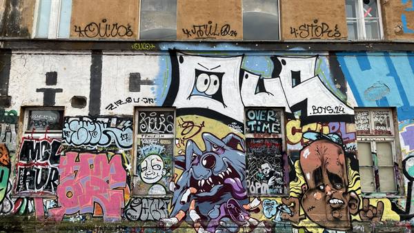 Dilapidated building facade covered in colorful graffiti, spray-painted window frames