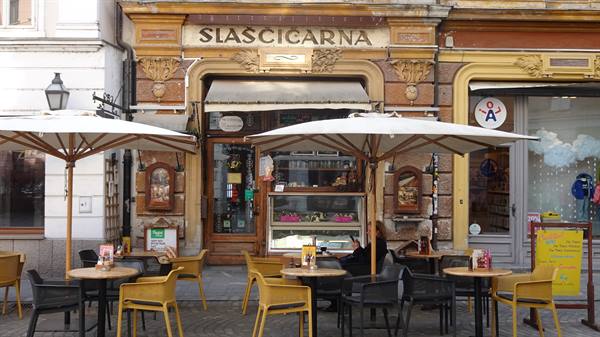 Café tables with umbrellas outside Slascicarna, an old bakery on an ornate golden facade