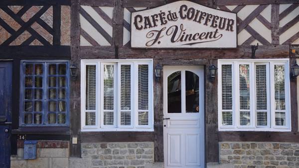 Cafè du Coiffeur F. Vincent sign on half-timbered facade, white door and windows