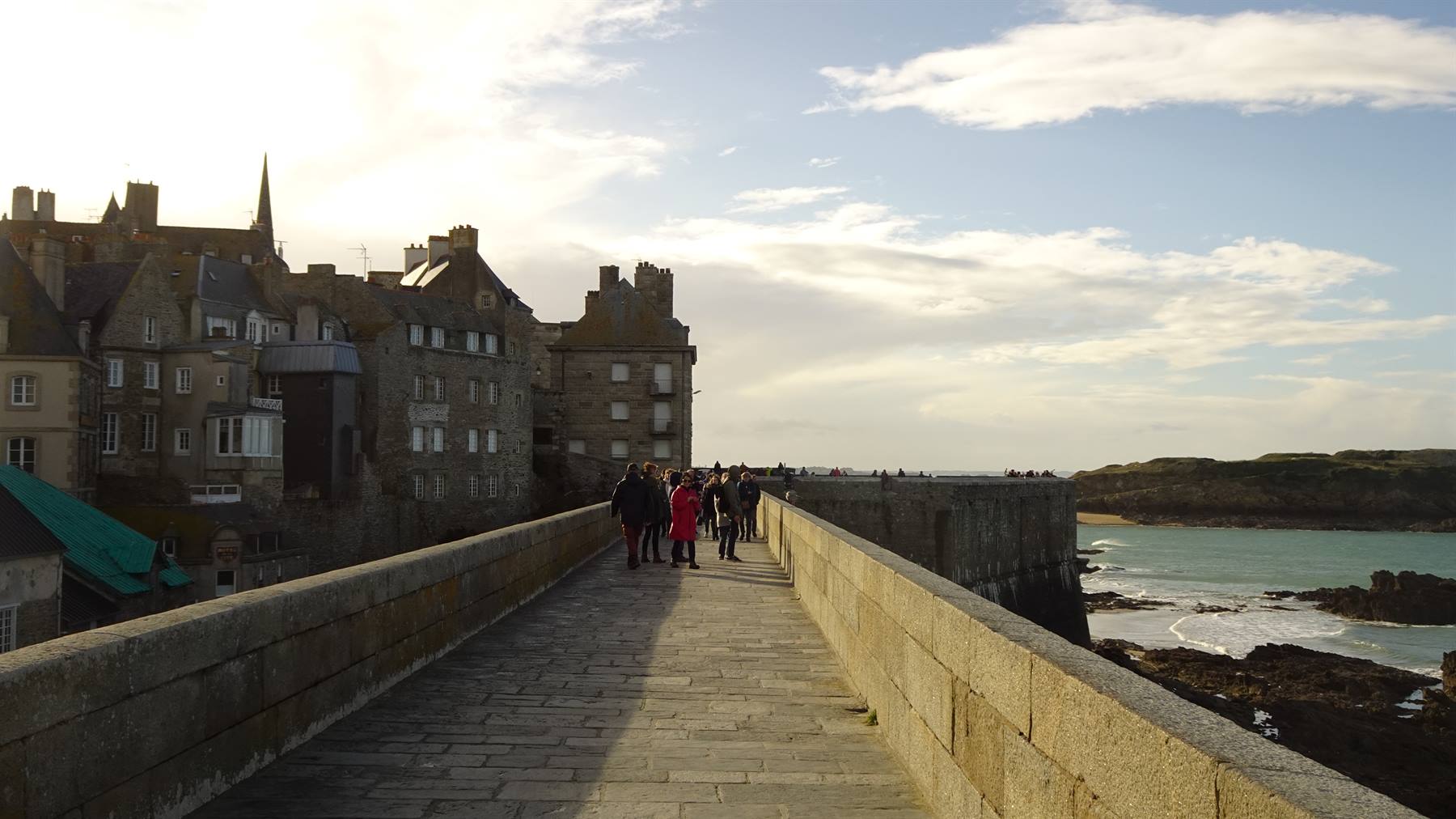 Turisti camminano sulla passerella in pietra verso la città fortificata di Saint-Malo