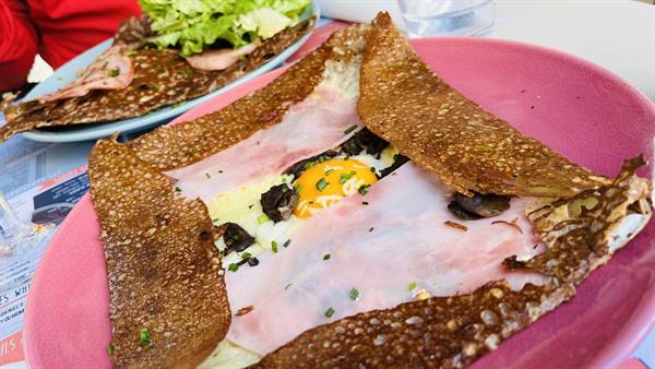 Buckwheat galette with ham, cheese and egg on a pink plate